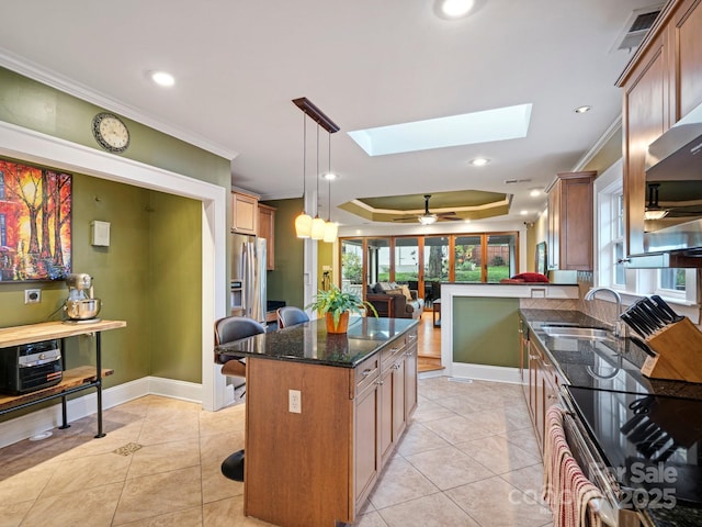 kitchen with sink, a skylight, a tray ceiling, pendant lighting, and ceiling fan