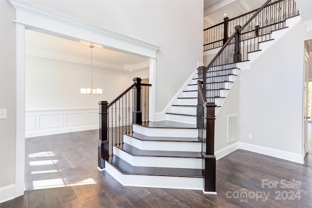 stairs featuring ornamental molding, a notable chandelier, and hardwood / wood-style floors