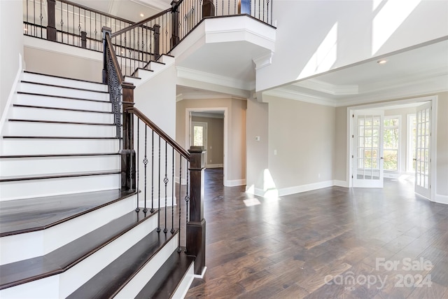 foyer entrance with french doors, dark hardwood / wood-style floors, a high ceiling, and ornamental molding