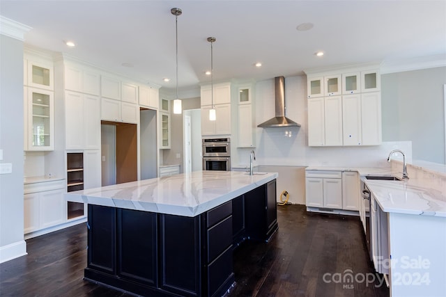 kitchen with wall chimney exhaust hood, a kitchen island with sink, and sink