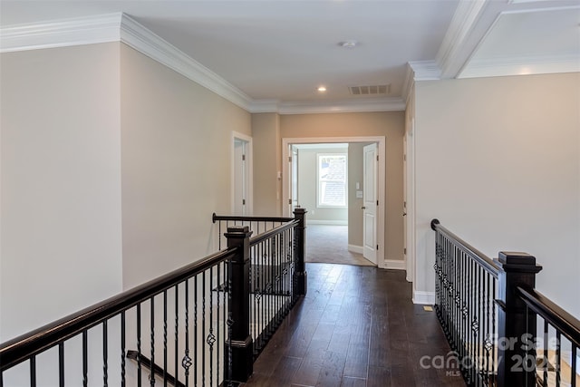 corridor with dark wood-style flooring, baseboards, an upstairs landing, visible vents, and ornamental molding