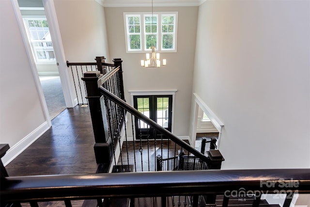 staircase featuring ornamental molding, hardwood / wood-style flooring, a wealth of natural light, and a chandelier