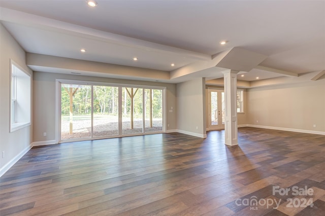 unfurnished living room featuring dark wood-type flooring, ornate columns, and beamed ceiling