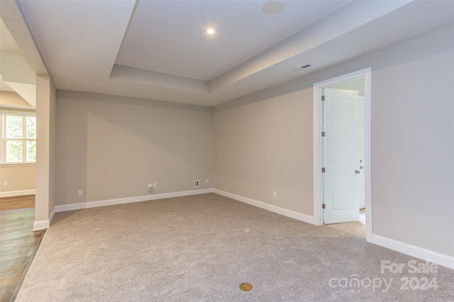 spare room with visible vents, baseboards, recessed lighting, light colored carpet, and a tray ceiling
