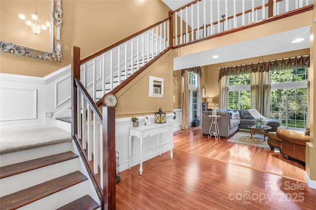 staircase with hardwood / wood-style flooring, a towering ceiling, and a notable chandelier