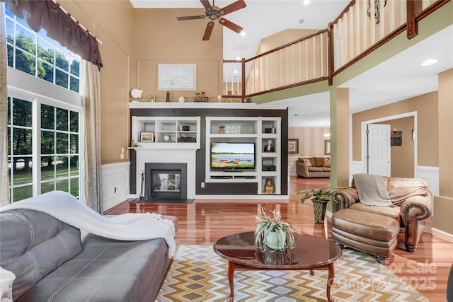 living room featuring a high ceiling, wood-type flooring, and ceiling fan