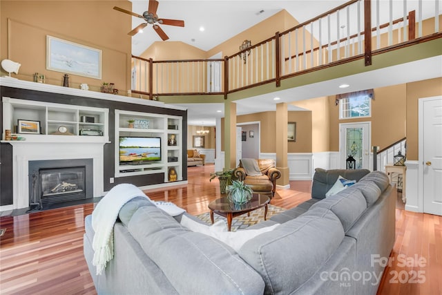 living room with ceiling fan, a towering ceiling, and wood-type flooring