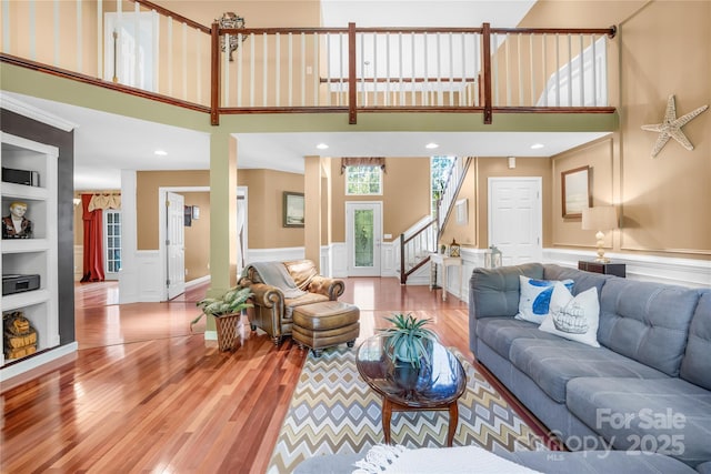 living room with built in shelves, wood-type flooring, and a high ceiling