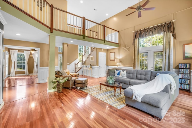 living room featuring a towering ceiling, a wealth of natural light, light hardwood / wood-style floors, and french doors