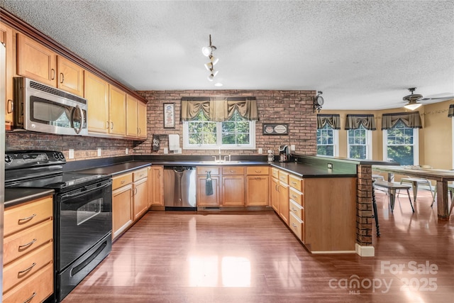 kitchen with sink, a textured ceiling, appliances with stainless steel finishes, kitchen peninsula, and ceiling fan