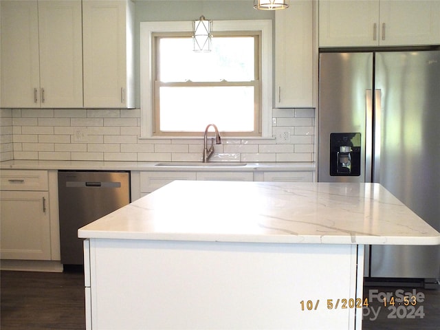 kitchen with backsplash, light stone countertops, stainless steel appliances, decorative light fixtures, and sink