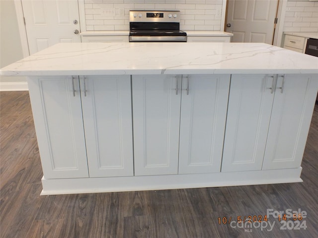 kitchen with stainless steel electric range, tasteful backsplash, a kitchen island, light stone countertops, and dark hardwood / wood-style flooring