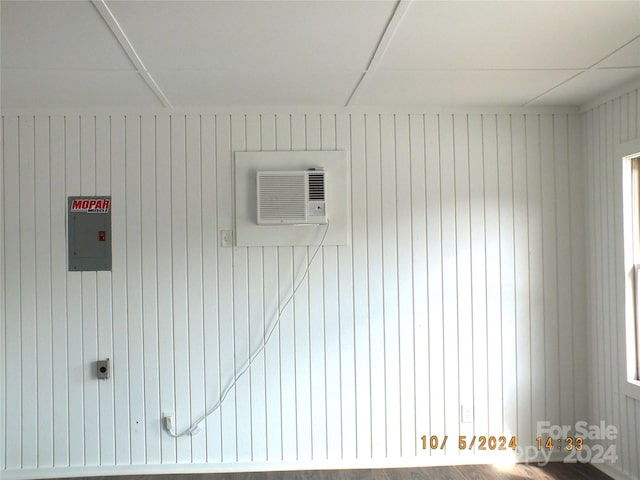 interior space with wood walls, electric panel, and a wall mounted AC