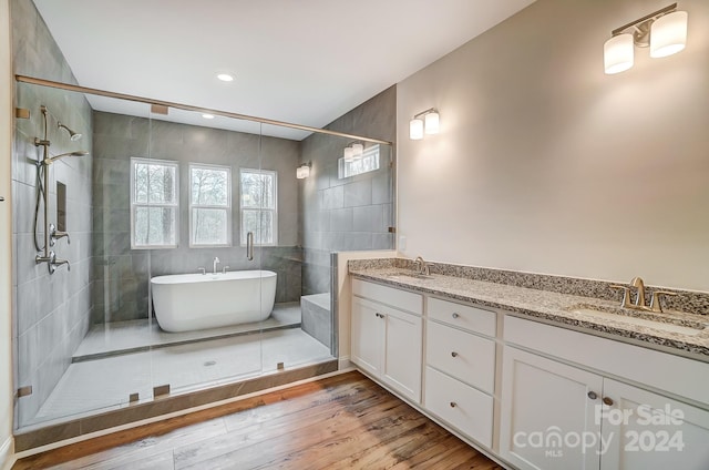 bathroom with independent shower and bath, vanity, tile walls, and hardwood / wood-style floors