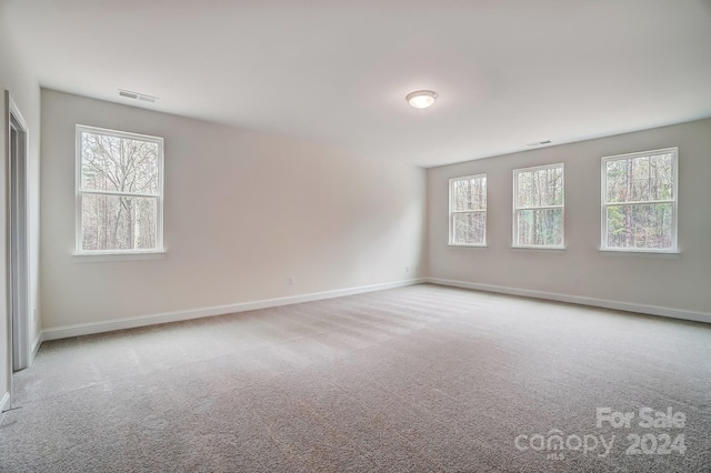 carpeted spare room featuring visible vents and baseboards