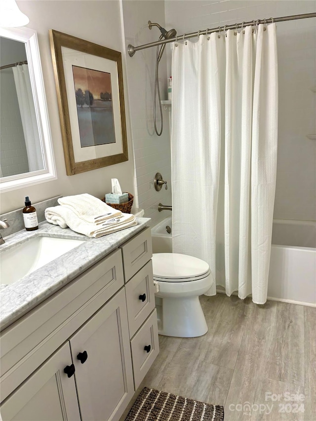 full bathroom featuring wood-type flooring, shower / bath combination with curtain, vanity, and toilet