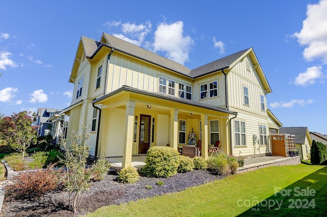 rear view of house featuring a porch and a lawn