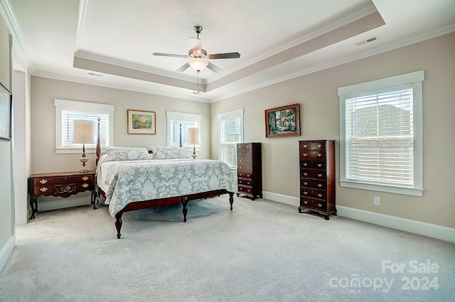 carpeted bedroom with a tray ceiling, multiple windows, and ceiling fan