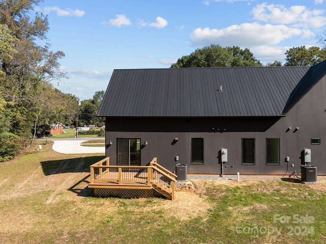 rear view of house featuring central AC unit, a lawn, and a deck