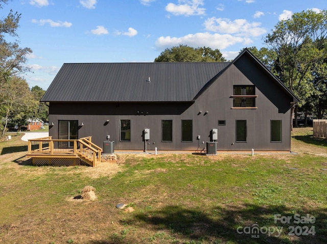 back of house featuring central air condition unit, a wooden deck, and a yard