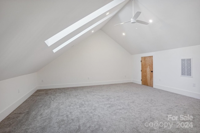 additional living space featuring vaulted ceiling with skylight, ceiling fan, and carpet flooring