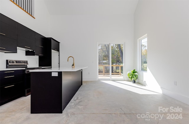 kitchen with a high ceiling, a center island with sink, a breakfast bar, and range with electric stovetop