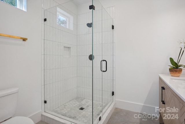 bathroom with an enclosed shower, a wealth of natural light, vanity, and toilet