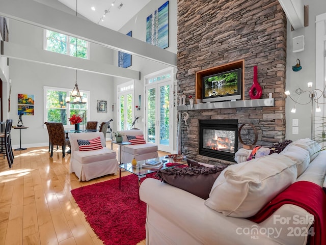 living room featuring light wood-type flooring, high vaulted ceiling, and a fireplace