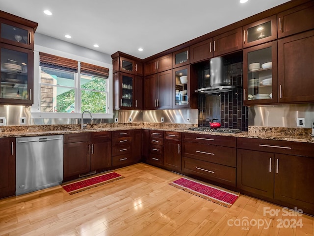 kitchen featuring sink, backsplash, exhaust hood, appliances with stainless steel finishes, and light hardwood / wood-style floors