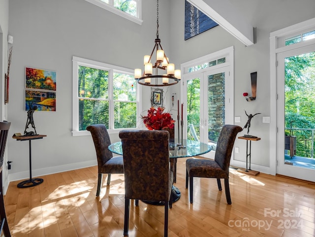 dining area featuring light hardwood / wood-style flooring, a chandelier, and a high ceiling