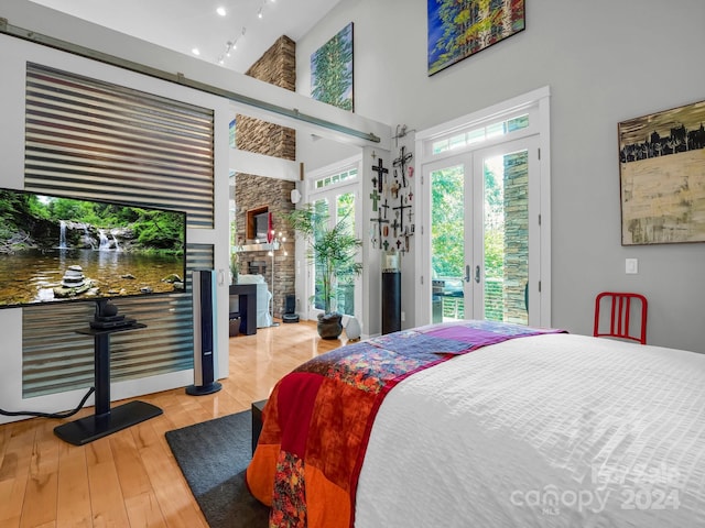 bedroom with access to outside, french doors, a high ceiling, and hardwood / wood-style flooring