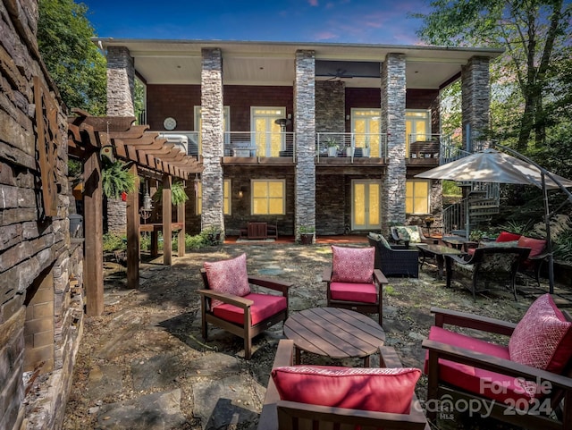 patio terrace at dusk with outdoor lounge area, a pergola, and a balcony