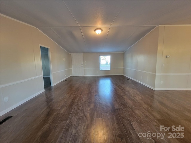 interior space with dark wood-style flooring, visible vents, baseboards, and vaulted ceiling