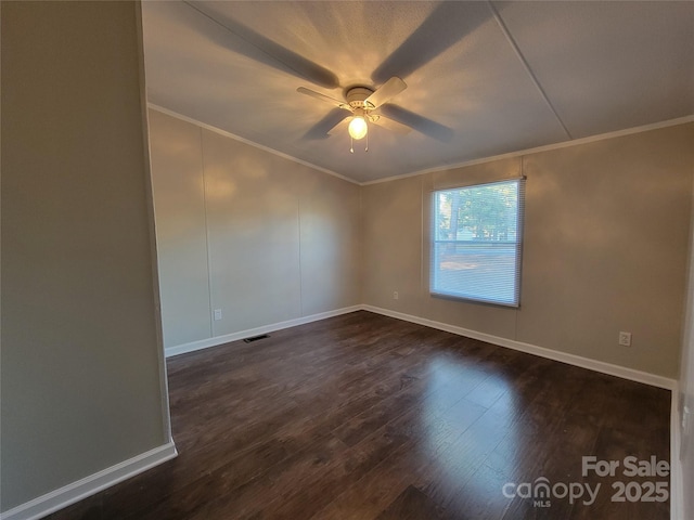 spare room featuring crown molding, dark wood finished floors, baseboards, and a ceiling fan