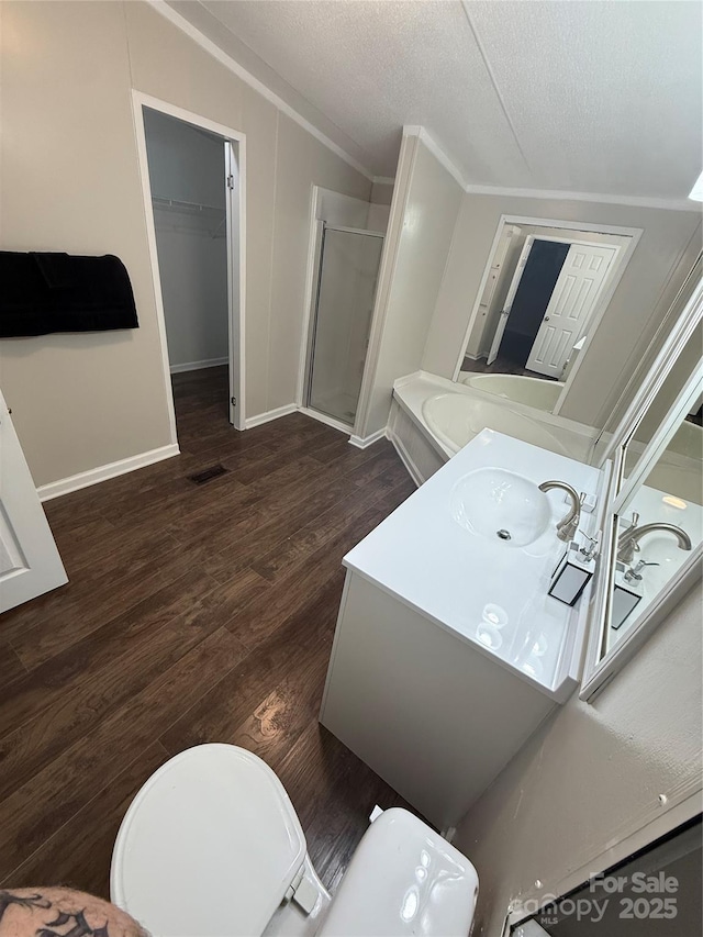 full bathroom with vanity, crown molding, a shower stall, visible vents, and wood finished floors