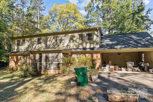 back of house with a sunroom and a lawn