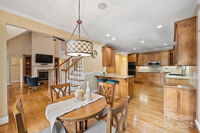 dining area with crown molding, light hardwood / wood-style floors, and sink