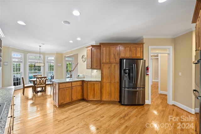 kitchen featuring stainless steel refrigerator with ice dispenser, light hardwood / wood-style floors, hanging light fixtures, and crown molding