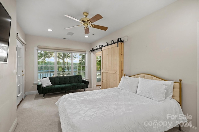 bedroom with a barn door, light carpet, and ceiling fan