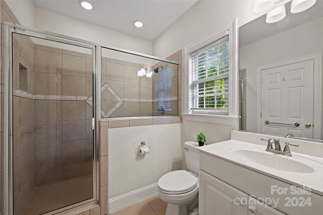 bathroom with vanity, tile patterned flooring, toilet, and a shower with door