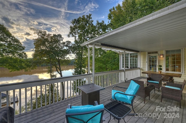 deck at dusk featuring a water view and outdoor lounge area