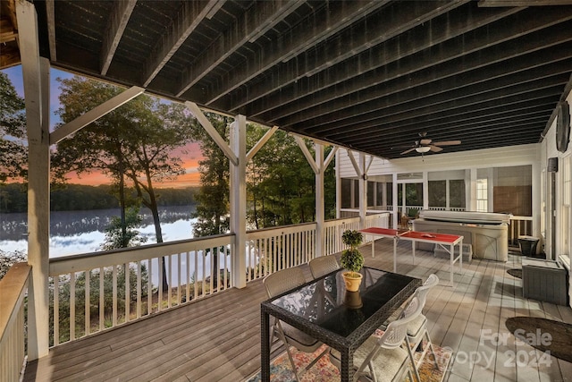 deck at dusk featuring a water view and ceiling fan