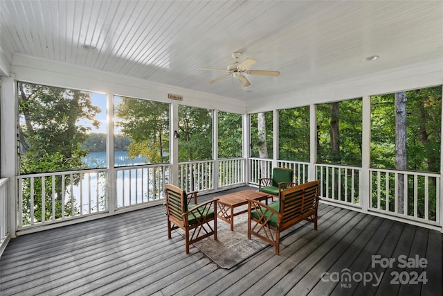 sunroom with ceiling fan and a water view