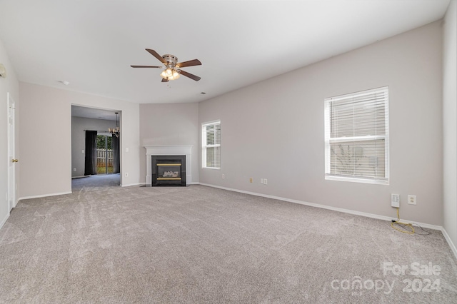 unfurnished living room with ceiling fan, a wealth of natural light, and light colored carpet