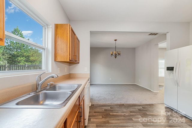 kitchen featuring white appliances, dark hardwood / wood-style flooring, a notable chandelier, sink, and hanging light fixtures