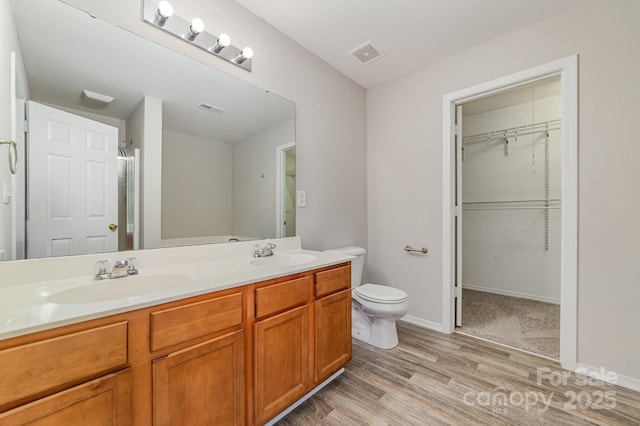 4803 Roxfield Ln, Charlotte, NC 28215 - full bathroom with wood finished floors, toilet, double vanity, a walk in closet, and baseboards