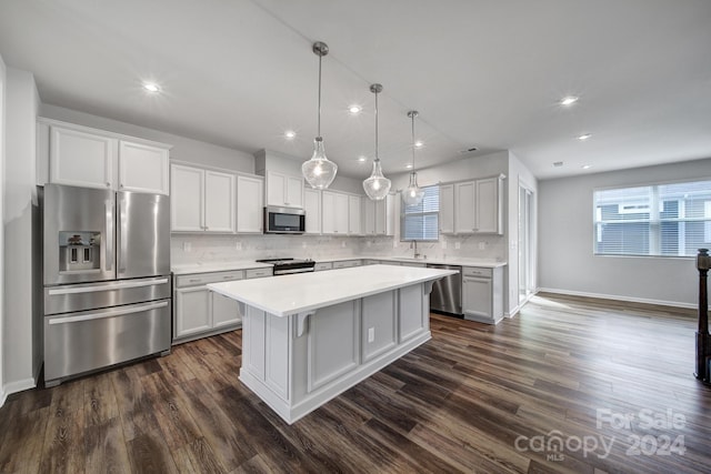 kitchen with dark wood-type flooring, stainless steel appliances, backsplash, a center island, and pendant lighting