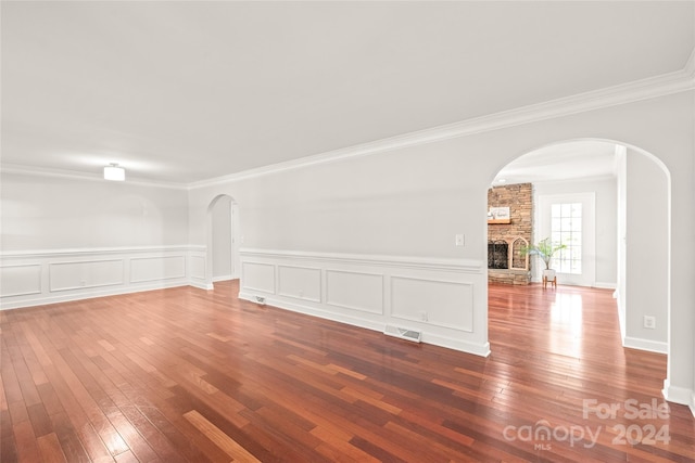 spare room with crown molding, a fireplace, and hardwood / wood-style floors