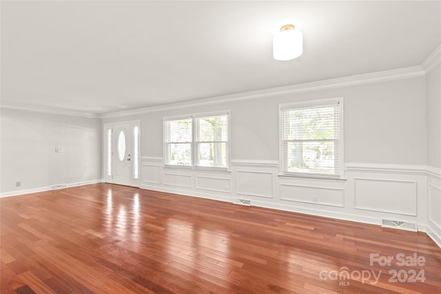 unfurnished room with wood-type flooring, a wealth of natural light, and ornamental molding