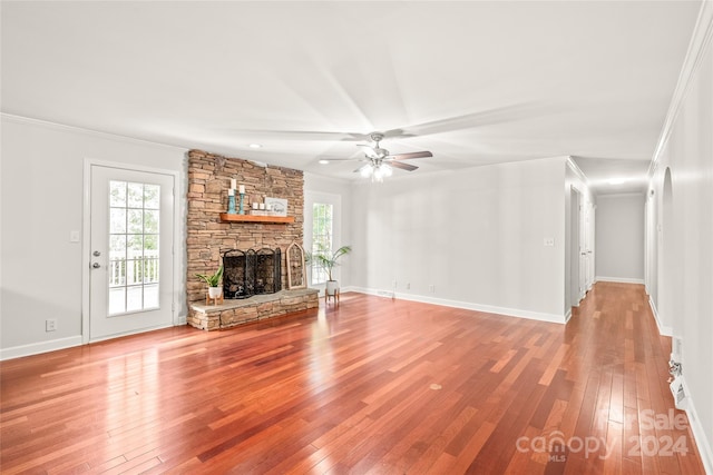 unfurnished living room featuring crown molding, a stone fireplace, light hardwood / wood-style flooring, and ceiling fan